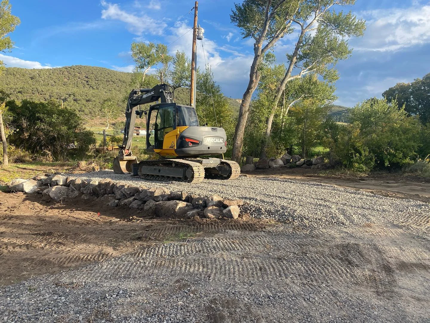 A Sergeant & Sons excavator on a gravel driveway surrounded by Colorado hills